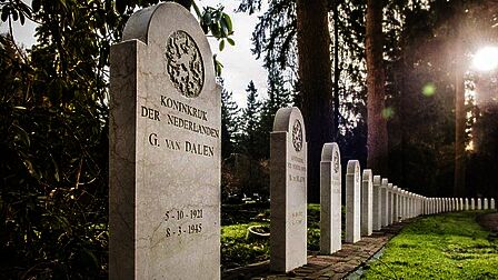Oorlogsgraven op een rij met elk een crèmekleurige staande grastenen met een afgerond bovenkant.